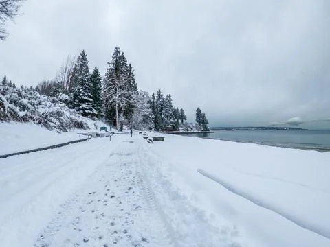 Vancouver's seawall at Third Beach covered in snow, displaying a serene whi.. Stock Photos