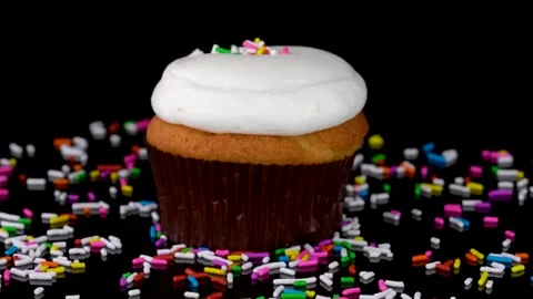 Vanilla Cupcake with Sprinkles Rotating on Reflective Surface Stock Footage 330517513