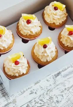 Vanilla cupcakes with a cap of cream on white wooden tablein the box Stock Photos