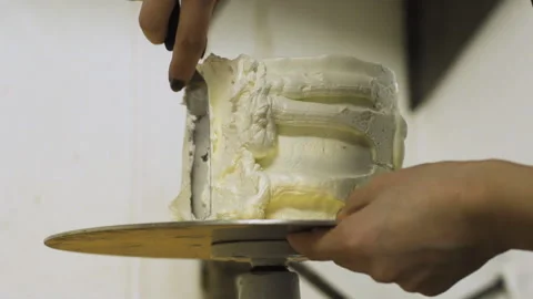 Vanilla frosting being spread on the side of a cake Stock Footage 130587666