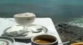 Vanilla ice cream in bowl and a cup of coffee on sea background HD Footage