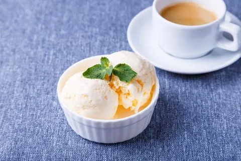 Vanilla ice cream with mint in a white plate and a cup of espresso. Stock Photos