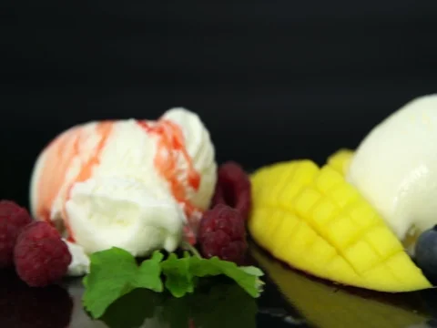 Vanilla ice cream scoops with chocolate syrop, berries, nuts and mango Stock Footage 80417158