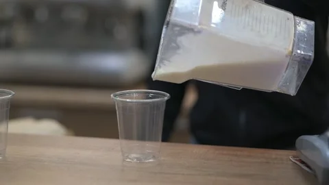 Vanilla milkshake is poured slowly into a plastic cup Stock Footage 169042435