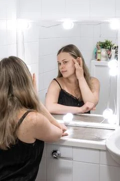 Vanity mirror reflection of female performing gentle skin touch as part of Stock Photos