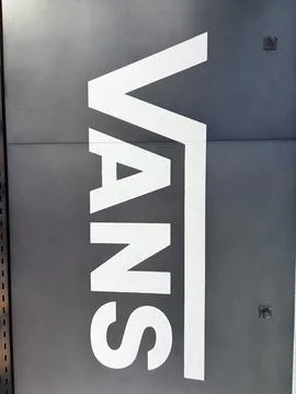 Vans iconic white logo displayed on a matte black textured wall surface at .. Stock Photos