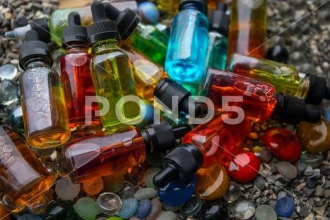 Vape concept. Beautiful colorful vape liquid glass bottles outdoor on stones. Stock Photos