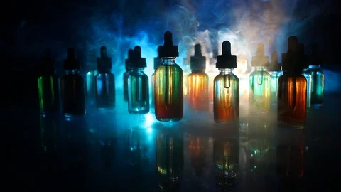 Vape concept. Smoke clouds and vape liquid bottles on dark background