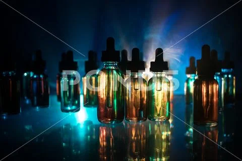 Vape concept. Smoke clouds and vape liquid bottles on dark background. Light Stock Photos