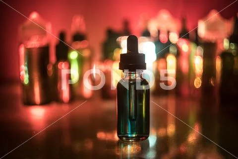 Vape concept. Smoke clouds and vape liquid bottles on dark background. Light Stock Photos