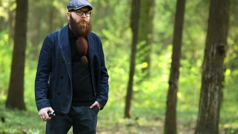 Vape man. Bearded man in a cap and glasses smokes an electronic cigarette. Stock Footage 107984547