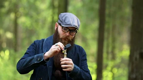 Vape man. Bearded man in a cap and glasses smokes an electronic cigarette. Stock Footage 108468150