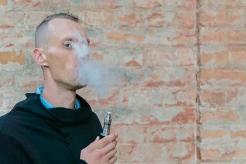 Vape man. Guy vaping electronic cigarette opposite vintage brick wall. Urban  Stock Photos