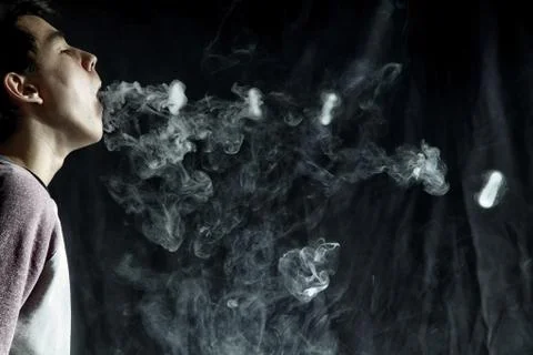 Vape trick rings in performance of vaper on dark background Stock Photos