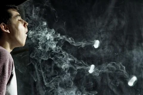 Vape trick rings in performance of vaper on dark background Stock Photos