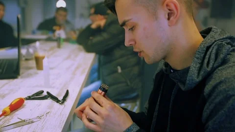Vape. White guy is regulating electronic cigarette coils. Stock Footage 73178469