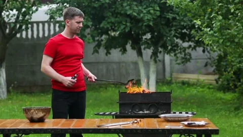 Vape. Young man preparing coals for kebabs and smoking an electronic cigarette Stock Footage 113183841