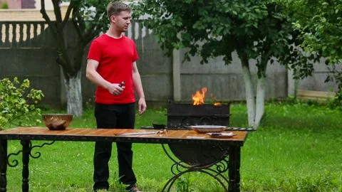 Vape. Young man preparing coals for kebabs and smoking an electronic cigarette Stock Footage 113183842