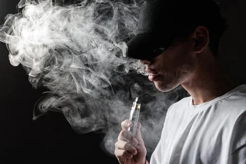 Vaper Exhaling Smoke from E-Cigarette in Dark Setting Stock Photos