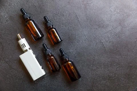 Vaping device e-cigarette electronic cigarette and liquid bottles on dark b.. Stock Photos