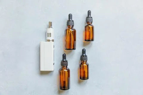 Vaping device e-cigarette electronic cigarette and liquid bottles on concre.. Stock Photos