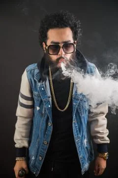 Vaping man holding a mod. A cloud of vapor. Black background. Vaping an Stock Photos