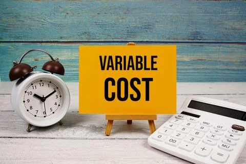 Variable Cost text written on paper card with calculator and alarm clock on.. 스톡 사진