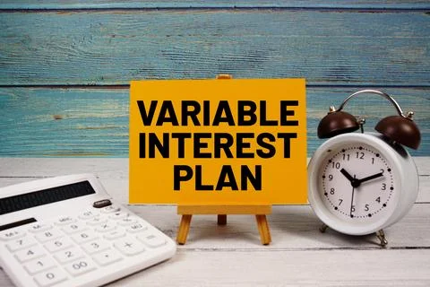 Variable Interest Plan text written on paper card with calculator and alarm.. Fotos de archivo