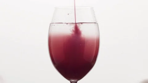 Variable speed closeup pour blueberry juice into water in wine glass Stock Footage
