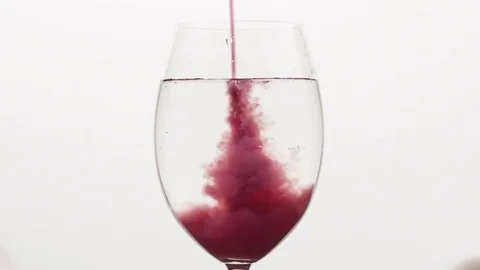 Variable speed closeup pour blueberry juice into water in wine glass Stock Footage
