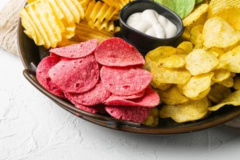 Variation different potato chips on white stone table background Stock Photos
