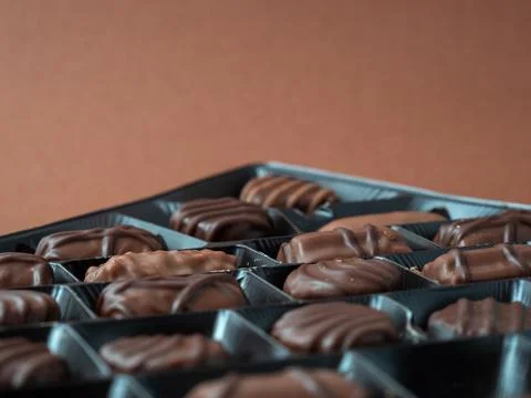 A varied assortment of chocolates arranged on a rich brown background. Stock Photos