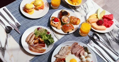 Variety breakfast spread on marble table with eggs Benedict, pastries, Stock Footage 318117482