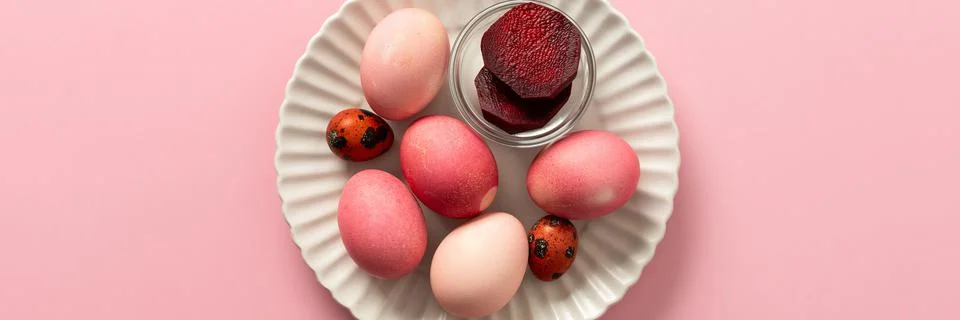 A variety of dyed Easter eggs in soft pink and vibrant shades rest on a decor Stock Photos