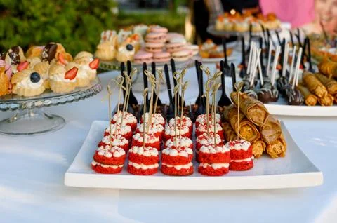 A variety of eclairs, macarons, and mini desserts on an outdoor buffet table Stock Photos