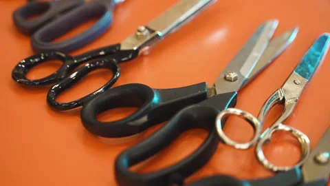 Variety of fabric scissors on working table surface in workshop, metal scissors Stock Footage 246977256
