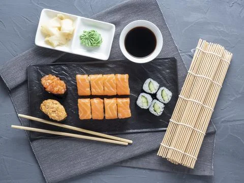 A variety of rolls and sushi gunkan nested on a black plate. next to it are b Stock Photos