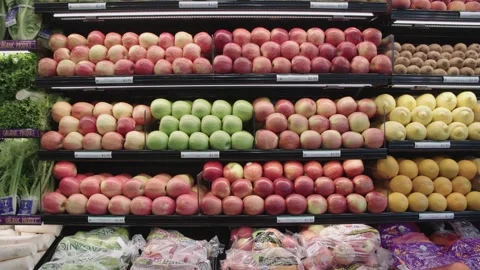 Various apples and citrus fruit on display shelves in the produce section Vidéo 243077093