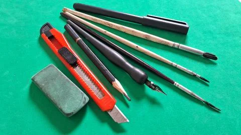 Various artistic drawing tools arranged neatly on a vibrant green surface Stock Photos