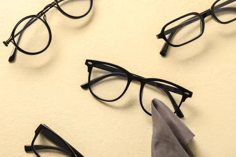 Various black eyeglasses on beige surface with cleaning cloth Stock Photos