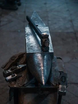 Various blacksmith tools around the anvil with a hammer. Stock Photos