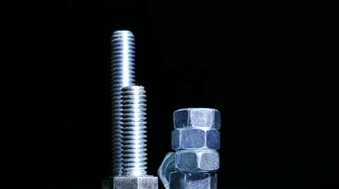 Various bolts  with nuts rotates against  dark background. 4K   shot Stockbeeldmateriaal 61459182