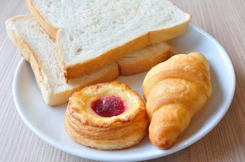 Various breads and croissants on breakfast table. Stock Photos