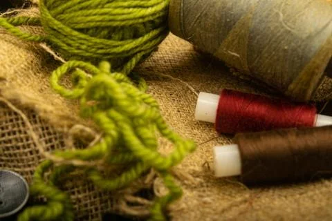 Various buttons and multicolored threads on coarse-textured burlap. Close up. Stock Photos