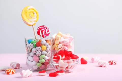Various candy and sweets on the table on a colored background. Stock Photos
