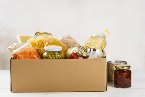 Various canned food, pasta and cereals in a cardboard box. Stock Photos