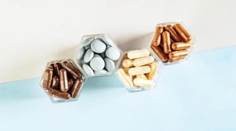 Various capsules with dietary supplements or medicines in honeycomb form jars Stock Photos