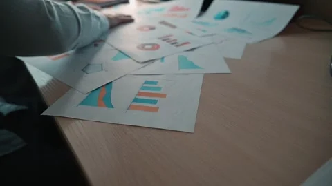Various charts and graphs are laid out on the table, a close-up of an economist Stock-Footage 338302650