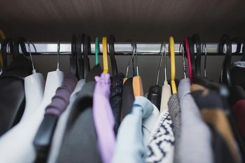 Various clothes randomly hanging on different hangers, close-up Stock Photos