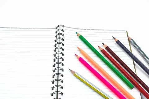 Various colored pencil crayons placed in a waved form line before a diary Stock Photos